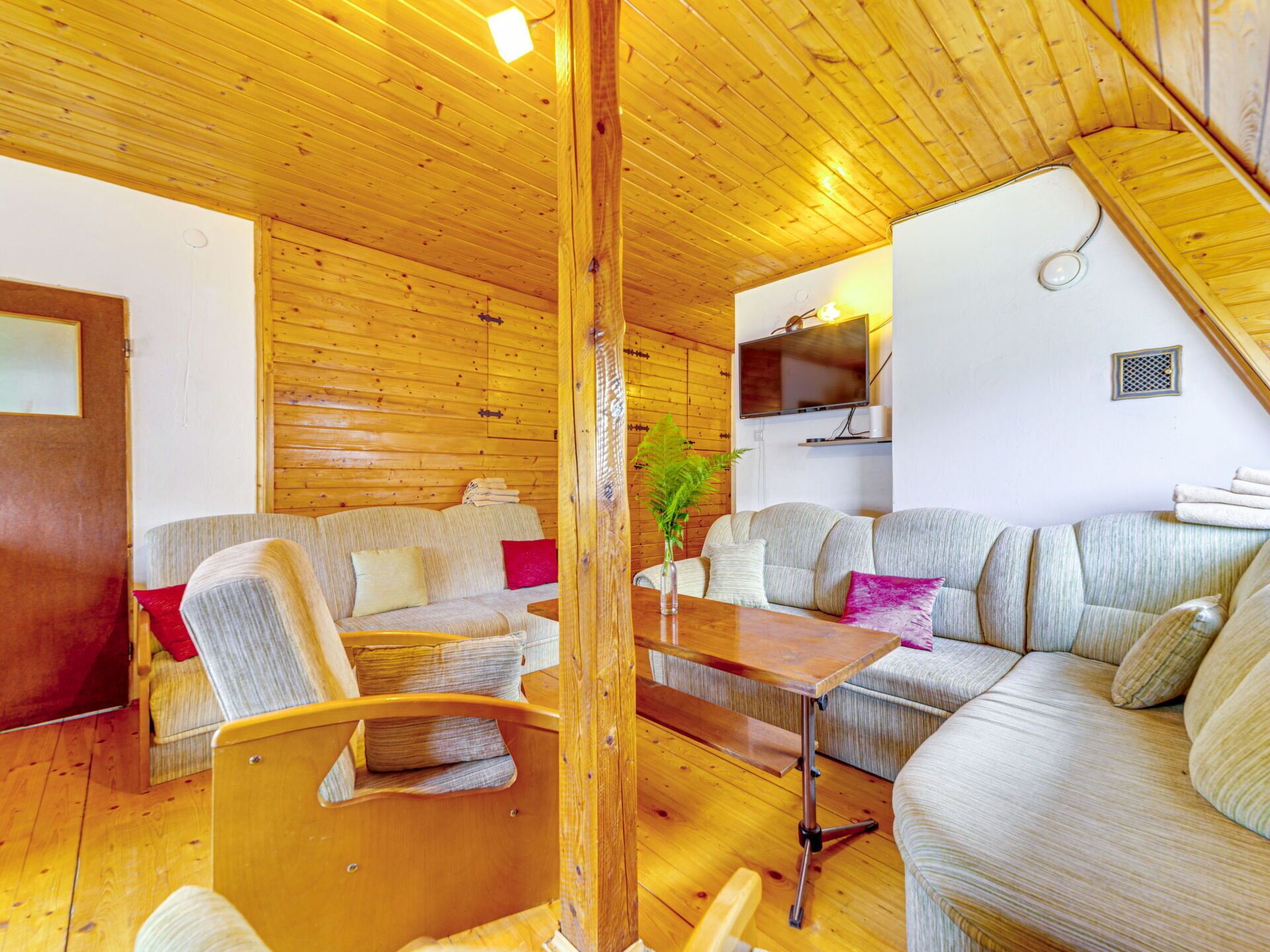 A cozy cabin interior with wooden walls and floors, a sofa, a chair, and a small table.