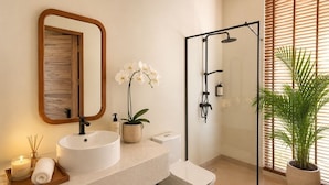 Ein Badezimmer mit Waschbecken, Spiegel, Dusche und Topfpflanzen.
