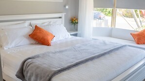 A neatly made bed with white and gray bedding, two orange pillows, and a gray throw blanket. - Stays with Ripley,
4bed, 2 bath pet friendly home only 3min drive to Hosp/beach! (Urraween)