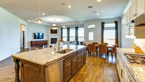 A spacious kitchen with a large island, wooden cabinets, and a built-in oven. - < 20 Mi to Fort Worth: Family-Friendly Aledo Home (Aledo)