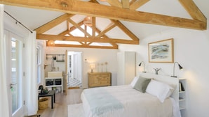 A bedroom with a large bed, wooden beams, a white wardrobe, and a painting on the wall.
