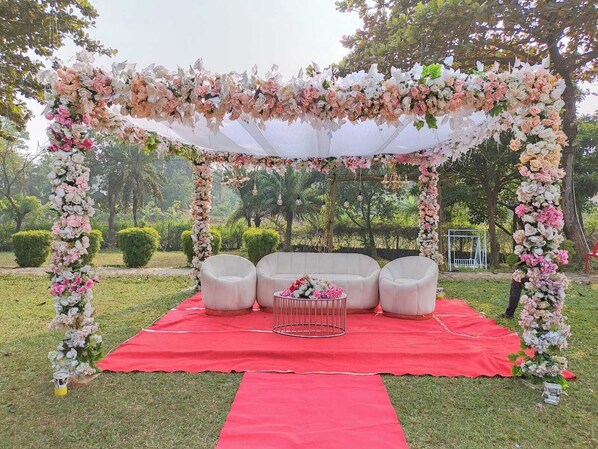 Une cérémonie de mariage en plein air, avec un dais blanc, des décorations florales et un tapis rouge.