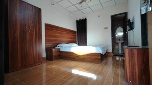 A bedroom with a wooden bed, a wardrobe, a bathroom with a sink, and a shower area. - Reverie Resort (Gazipur)