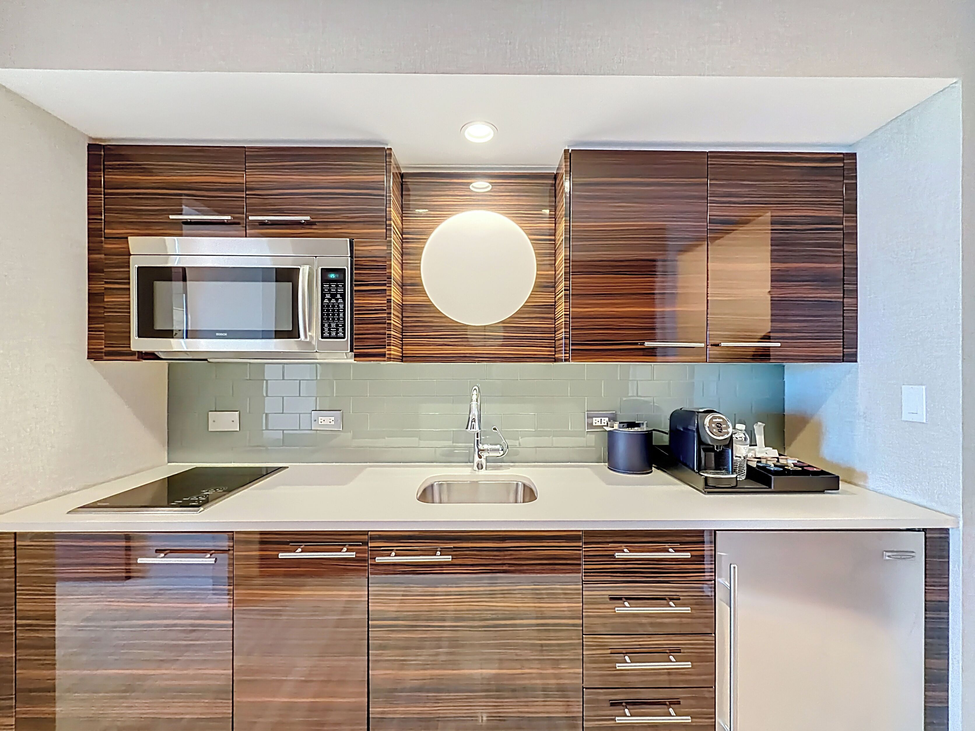 A modern kitchen with a built-in microwave, a sink, and wooden cabinets.