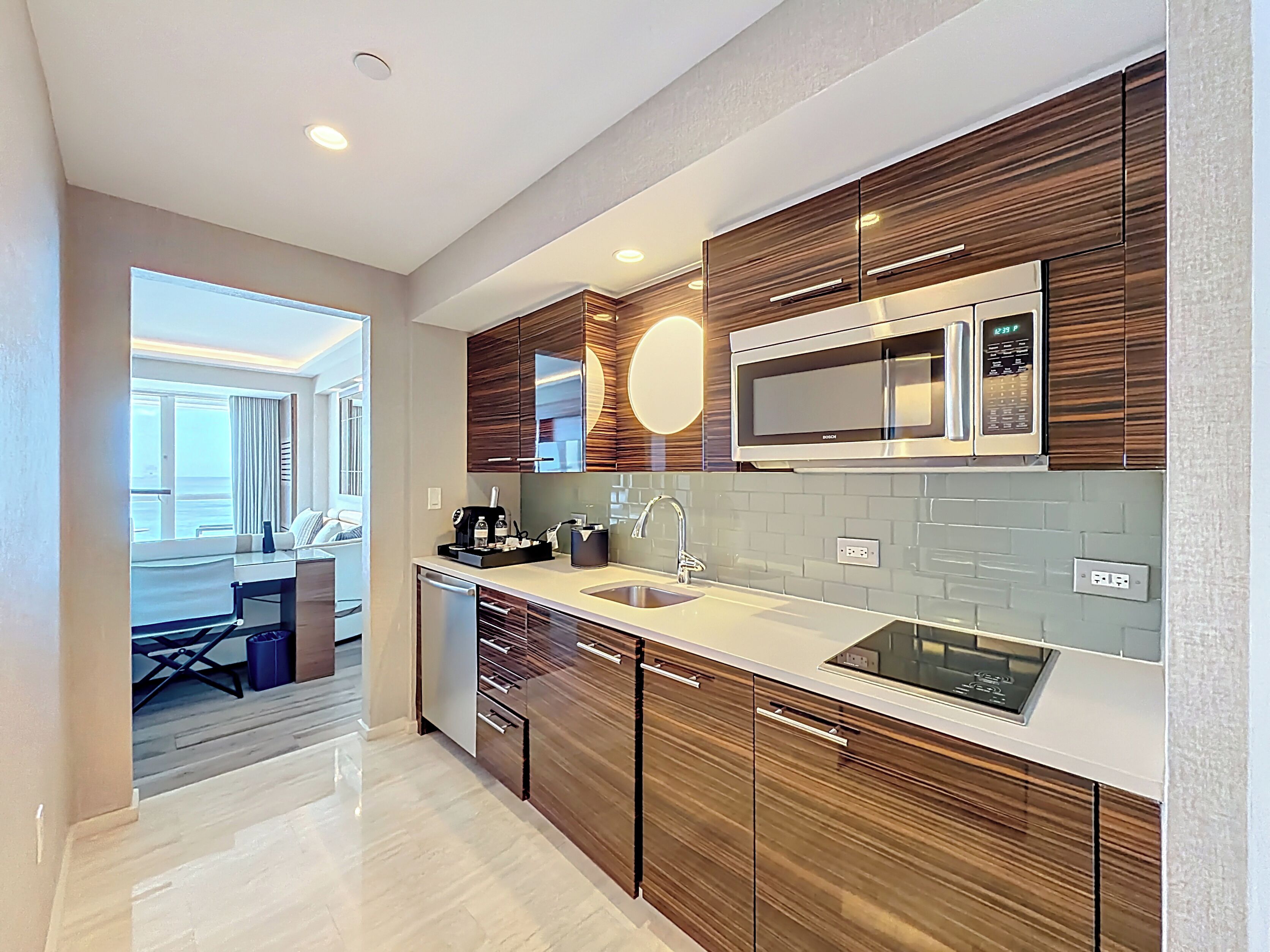 Una cocina moderna con gabinetes de madera, microondas integrado y un lavamanos.