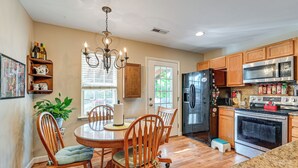 A kitchen with wooden cabinets, a stainless steel refrigerator, a microwave, and an oven. There is a dining table with chairs and a chandelier. - Wine & BBQ Trail Fun: Home w/ Hot Tub in Lexington (Lexington)