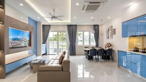 Una sala moderna con un sofá, televisor y comedor con sillas y una mesa.