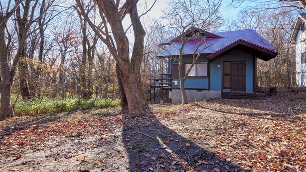 A small, single-story building with a red roof, surrounded by trees and fallen leaves. - rinne 2nd living Nasu Creek (Nasu)