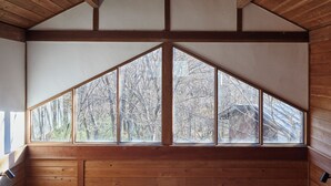 A room with a sloped ceiling and large windows offering a view of trees. - rinne 2nd living Nasu Creek (Nasu)