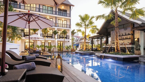 Un espace aménagé au bord de la piscine, avec des chaises longues, des parasols et un bassin décoratif.