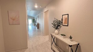 A hallway with a white console table, a potted plant, and framed artwork on the walls. - The paradise house in Roswell (Roswell)