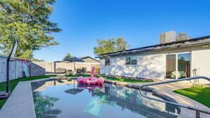 A swimming pool with a pink inflatable flamingo, a covered patio, and a modern house with a garage. - Easy Walk to Dtwn Gilbert, Family-Friendly Oasis! (Gilbert)
