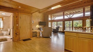 A spacious room with wooden flooring, a large window with a view, a television, and a cozy seating area. - Mountain-View Deck! Cabin By Mt Abraham Trails (Salem Township)