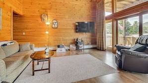 A wooden interior with a sofa, a coffee table, a flat-screen TV, and a view through large windows. - Mountain-View Deck! Cabin By Mt Abraham Trails (Salem Township)