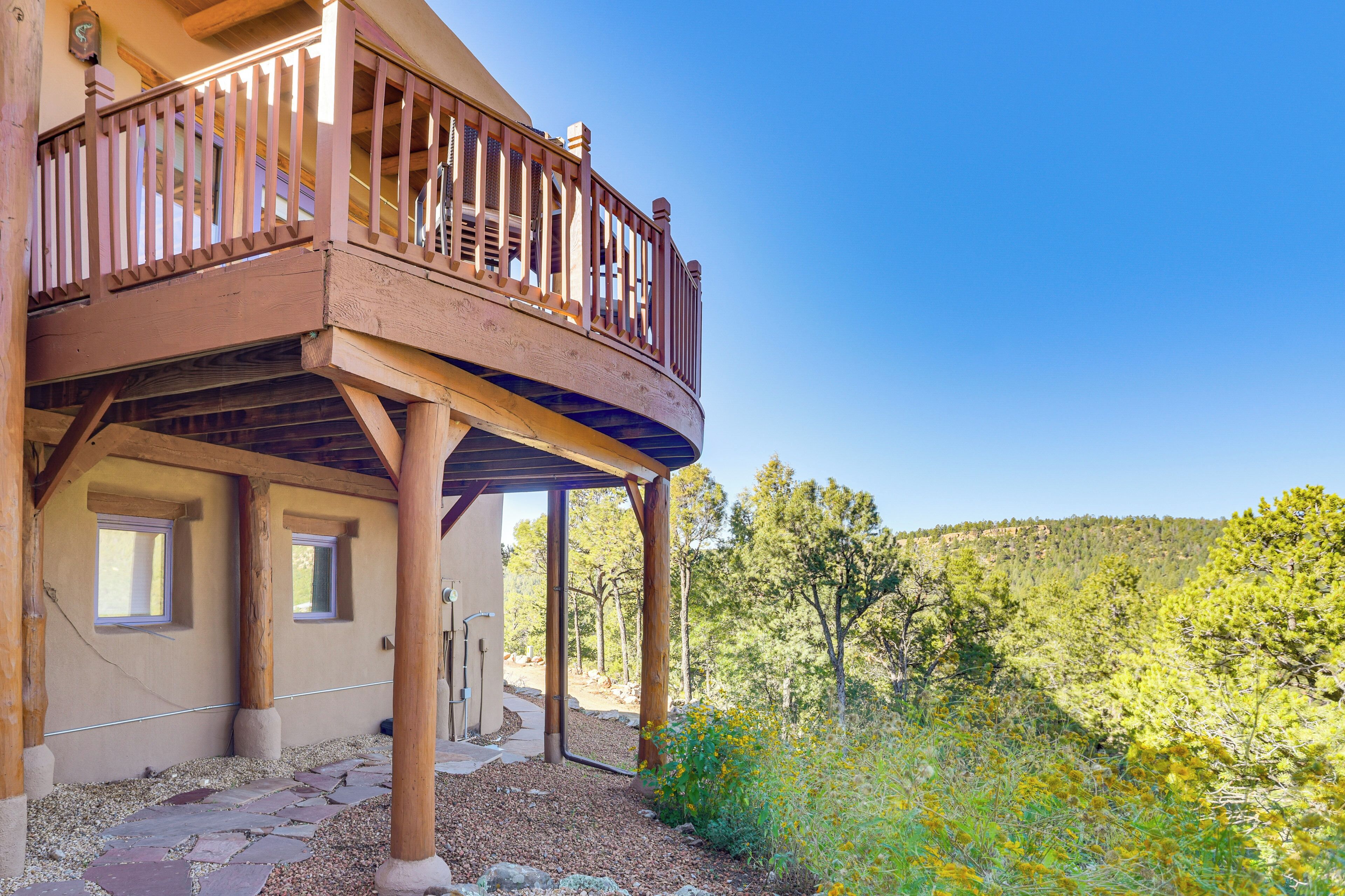 A wooden balcony with a view of a forested hillside.