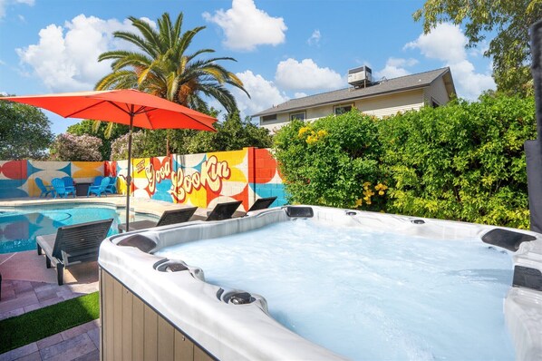 A hot tub with a colorful mural in the background, a pool, and a palm tree. - The Retro: Pool | Hot Tub | Basketball | Games (Mesa)