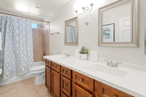 A bathroom with a double sink vanity, a toilet, a shower, and a large mirror. - The Retro: Pool | Hot Tub | Basketball | Games (Mesa)
