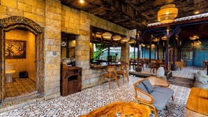 A traditional interior with stone walls, tiled flooring, wooden furniture, and a bar area. - Kamania Villa Ubud by Dhananjaya Hospitality (Sebatu)