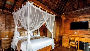 A wooden four-poster bed with a canopy, a television mounted on the wall, and a desk with a chair. - Kamania Villa Ubud by Dhananjaya Hospitality (Sebatu)