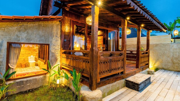 A wooden structure with a balcony, a stone wall, and a wooden floor. - Kamania Villa Ubud by Dhananjaya Hospitality (Sebatu)