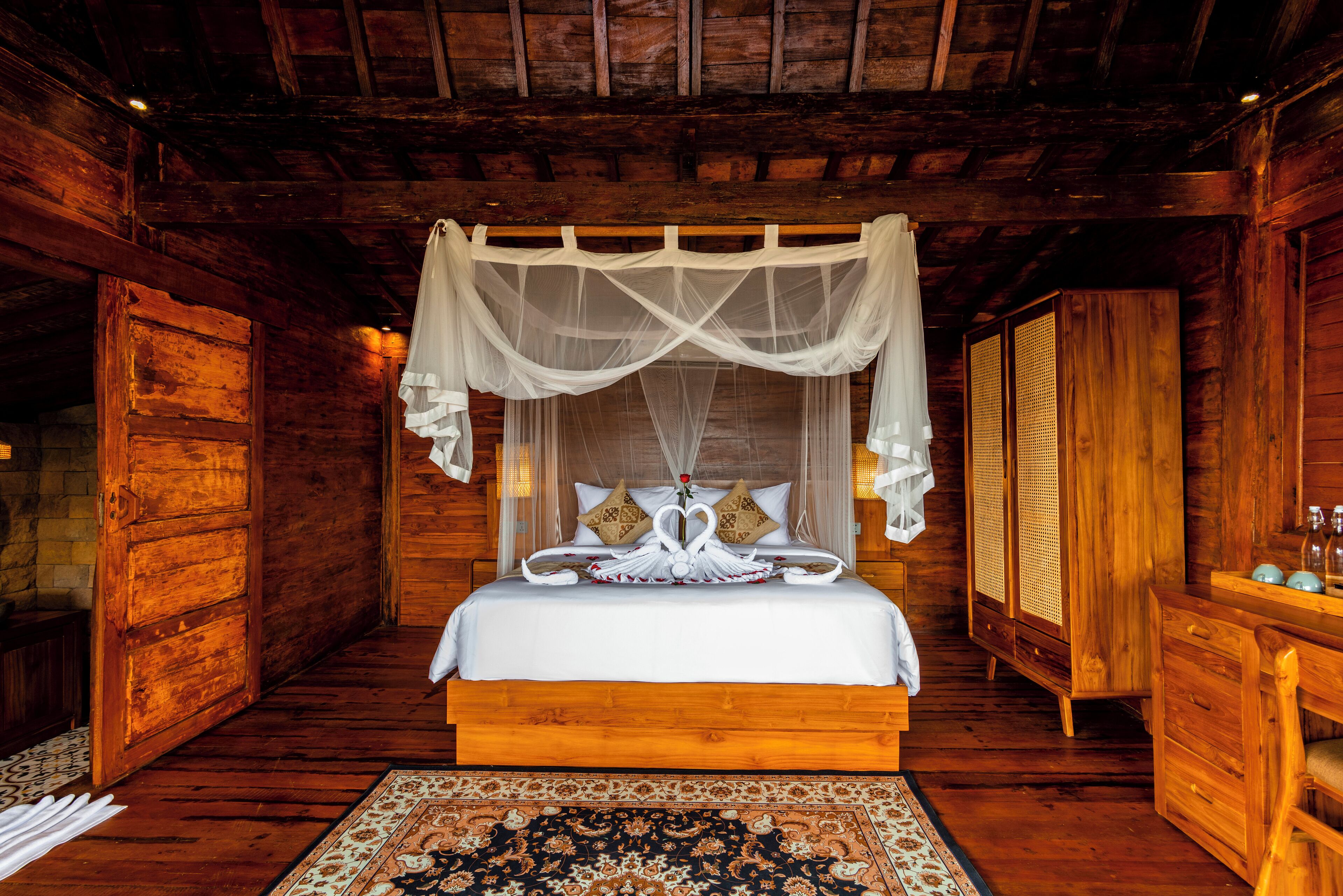 A wooden room with a bed, a nightstand, and a wardrobe.