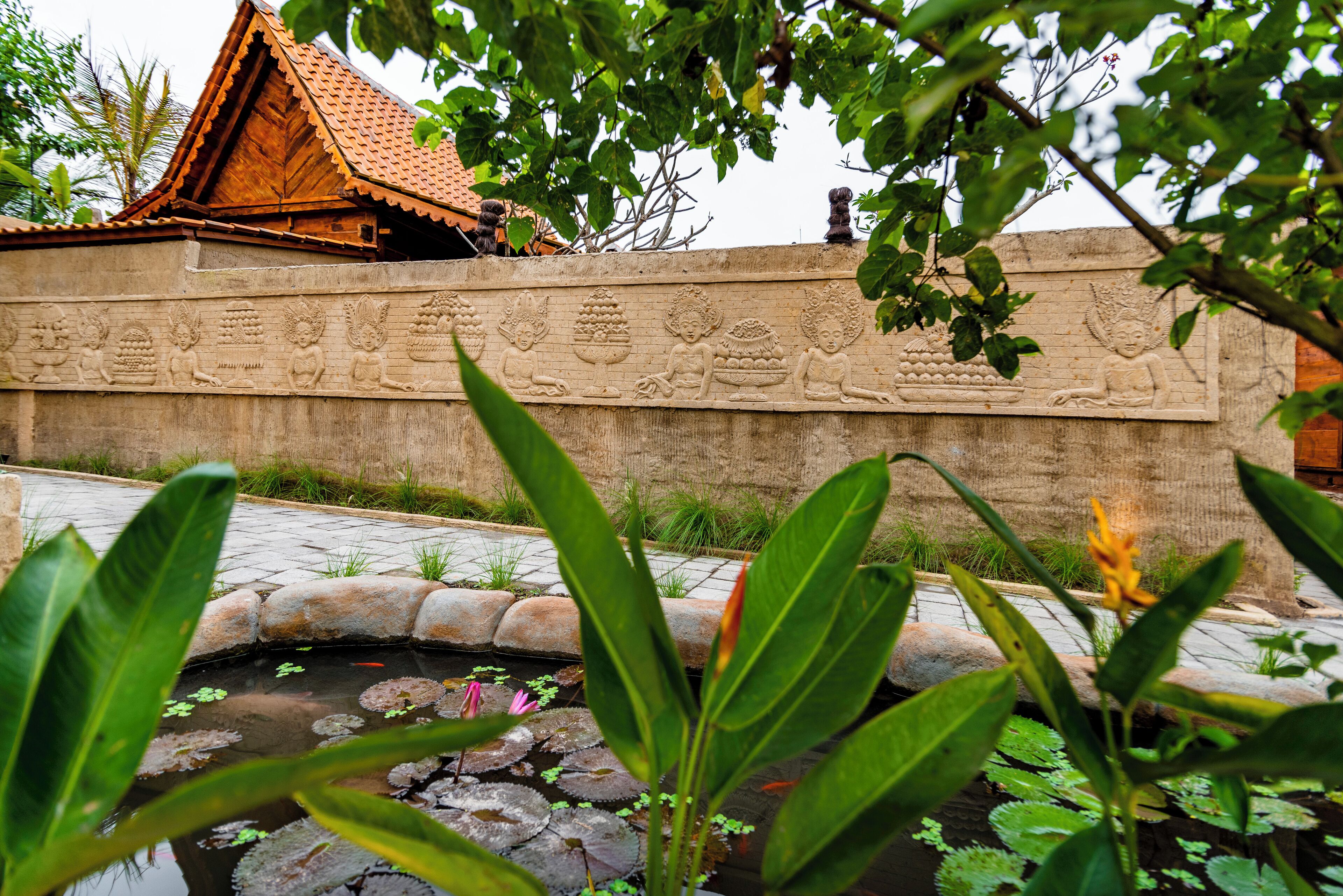 A traditional building with a tiled roof and a stone wall with carvings.
