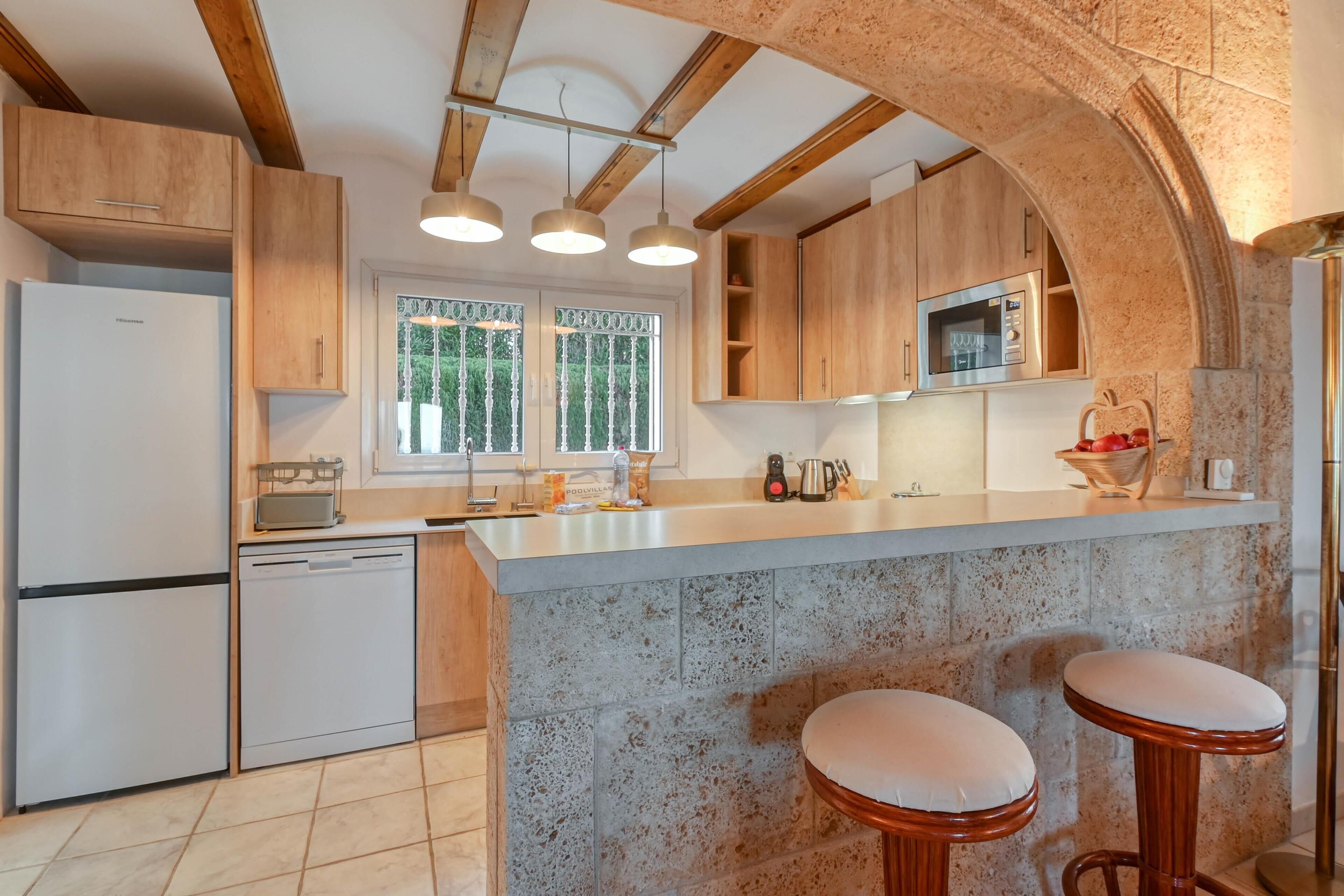 Eine moderne Küche mit Holzausstattung, einer integrierten Mikrowelle und einer großen Kücheninsel mit Sitzgelegenheiten.