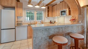 Una cocina moderna con armarios de madera, un microondas integrado y una isla grande con taburetes.