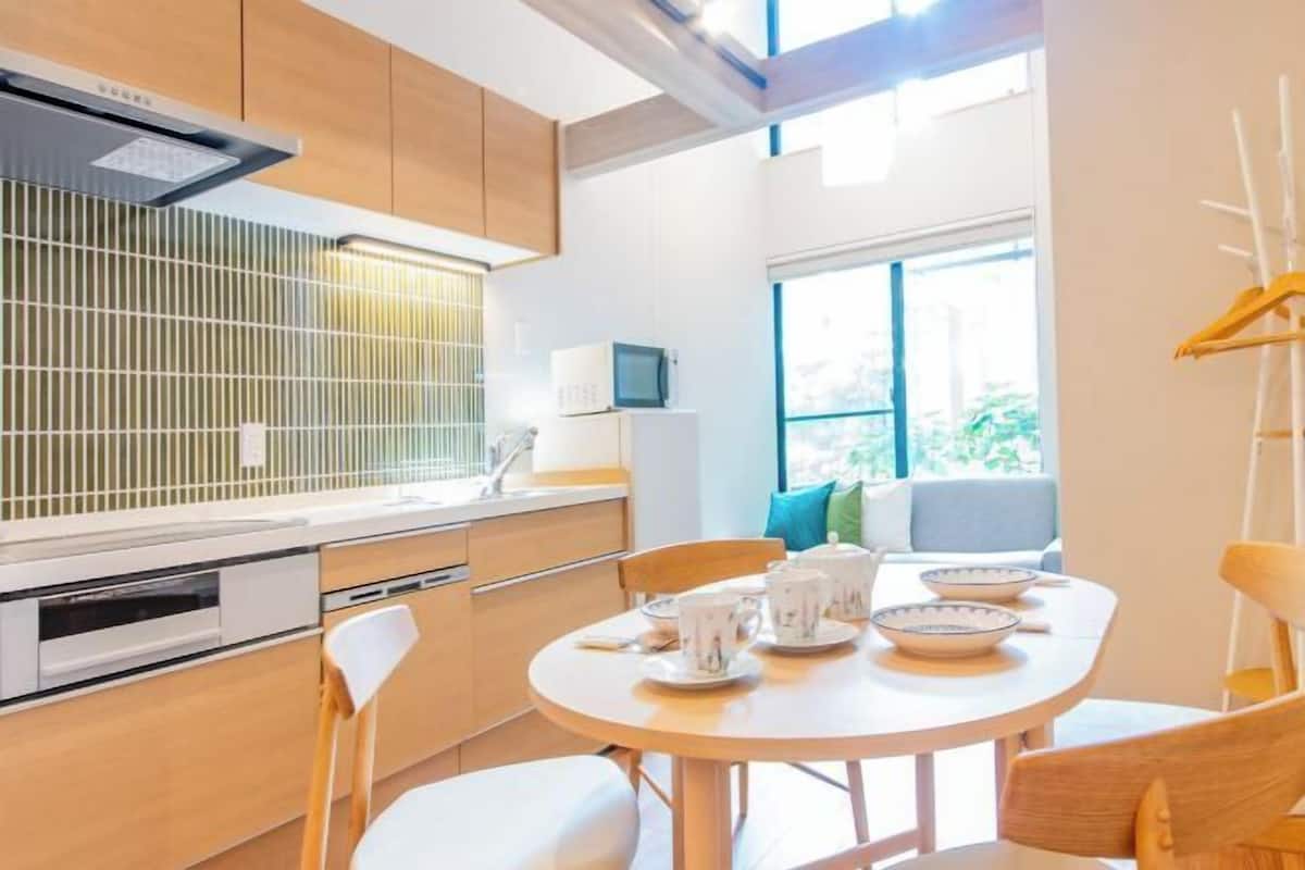 A modern kitchen with a round dining table, white appliances, and a view of the outdoors.