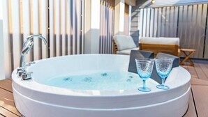 Tinaco con dos vasos sobre una terraza de madera, una silla y un muro de madera con listones verticales.