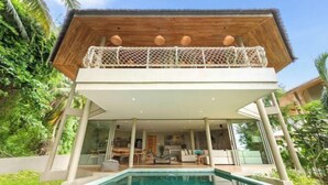 A modern villa with a glass-enclosed pool, a wooden deck, and a thatched-roof upper level. - Carbana Lodge, 2 Bedrooms - Eco Lodge, Koh Samui (Koh Samui)