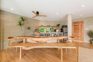 Une cuisine moderne avec un îlot central, des chaises en bois et un ventilateur de plafond.