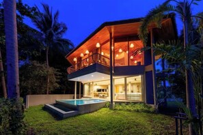 Une maison moderne à deux étages, dotée d’un balcon, d’une piscine et d’une pelouse bien entretenue.