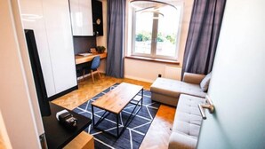 A compact living space with a kitchenette, a sofa, a dining table, and a window with curtains. - Nowolipki Studio, City Center Skyline View, WarsawStay (Warsaw)