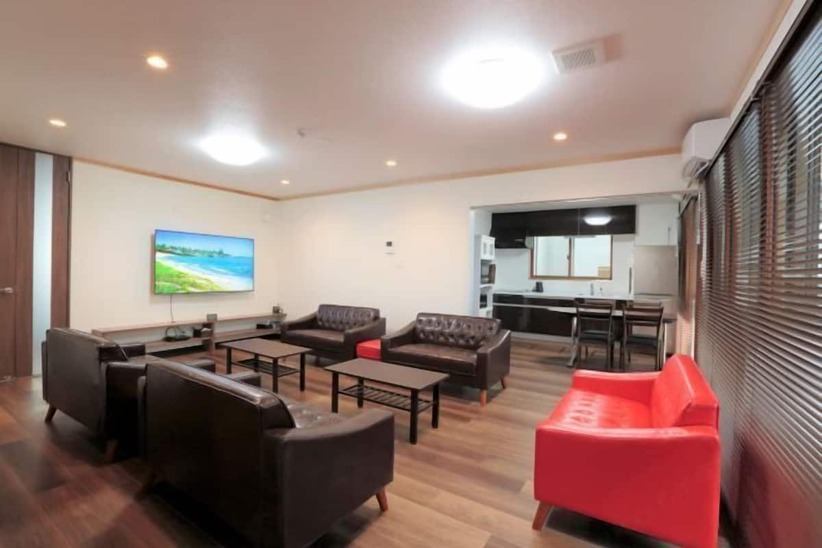 A modern hotel room with a living area, a kitchen, and a dining area.
