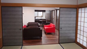 A traditional Japanese room with tatami flooring, a low wooden ceiling, sliding shoji doors, and a red sofa. - ROYAL SUITE SAKAE (Nagoya)