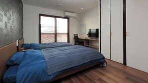 A bedroom with a bed, a desk, a TV, and a wardrobe. - ROYAL SUITE SAKAE (Nagoya)