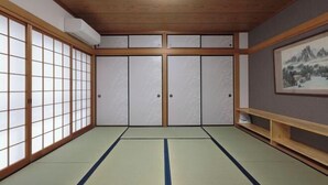 A traditional Japanese room with tatami flooring, sliding doors, and a framed picture on the wall. - ROYAL SUITE SAKAE (Nagoya)