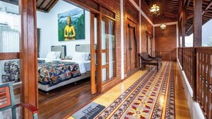 A room with a bed, a chair, a wooden ceiling, and a Buddha painting. - Joglo Wardani (Ngaglik)