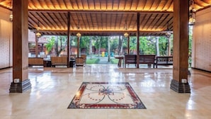 A covered outdoor area with a tiled floor, wooden pillars, and benches. - Joglo Wardani (Ngaglik)