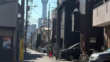 A narrow urban street with buildings, a bicycle, and a car parked on the side.