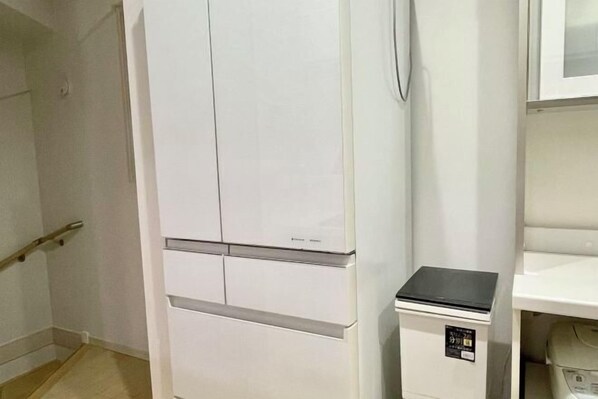 Habitació amb un armari blanc, un aparell petit de color negre i una estant blanca.