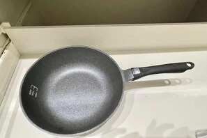 Eine schwarze Bratpfanne mit Henkel auf weißer Oberfläche.