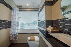 A bathroom with a bathtub, toilet, and a window with blinds. - Olivia Beach Sea and Sky Pool Villa Hua Hin (Cha-am)