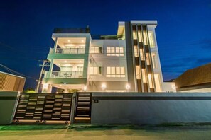A modern two-story building with a gated entrance, large windows, and a balcony on the upper floor. - Olivia Beach Sea and Sky Pool Villa Hua Hin (Cha-am)