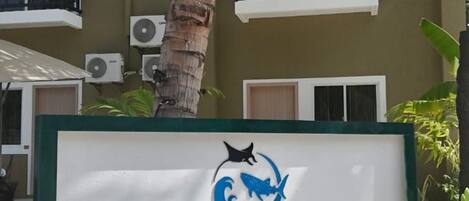 A sign for Seaside Hangethi Inn with a logo featuring a blue wave and a black silhouette of a person surfing.