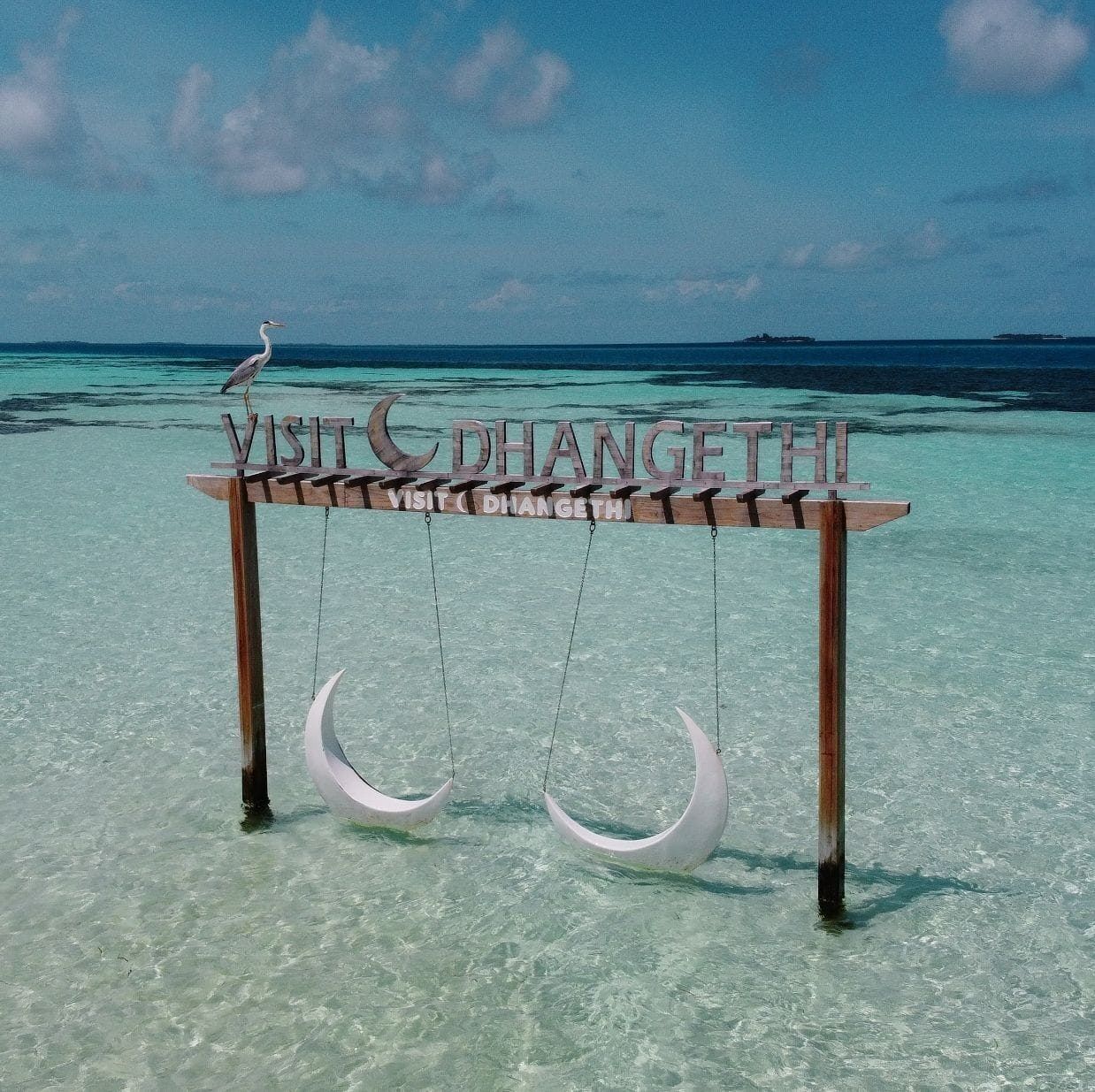 A wooden sign with the text "VISIT DHANGETHI" and crescent moon decorations.
