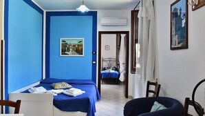Una camera da letto con una parete blu, un letto con copripiumino blu, una sedia e una scrivania.