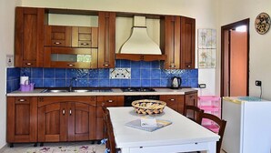 Cucina con mobili in legno, un piano di lavoro bianco e un rivestimento a mosaico blu.