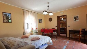 Une pièce comprenant un lit, un bureau, une chaise, une table à manger et un coin cuisine.